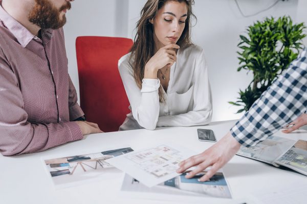 Young couple in talking to real estate agent.  Looking at a model of their new house in real estate agency office.